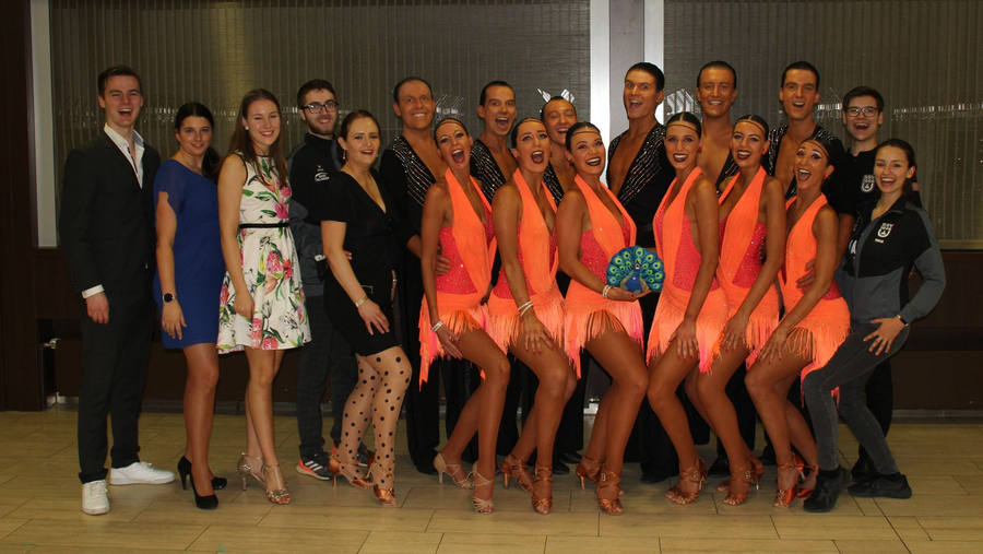 Smiling dance team in orange fringe costumes posing with supporters