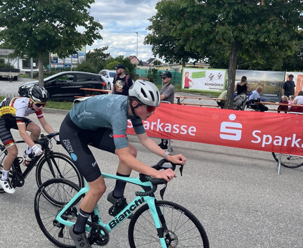 Jugendlicher Radfahrer in hellblauem Trikot auf Bianchi-Rennrad vor Sparkasse-Banner