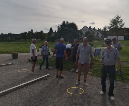 Gruppe älterer Männer spielt Boule auf Kiesplatz im Freien