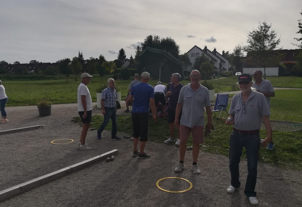 Gruppe älterer Männer spielt Boule auf Kiesplatz im Freien