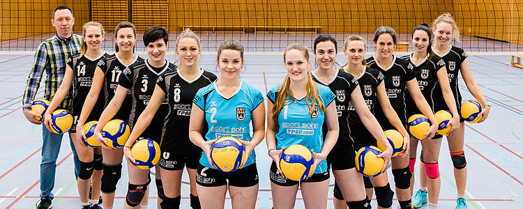 Volleyballteam des SSV Ulm in Sporthalle mit Volleyballbällen