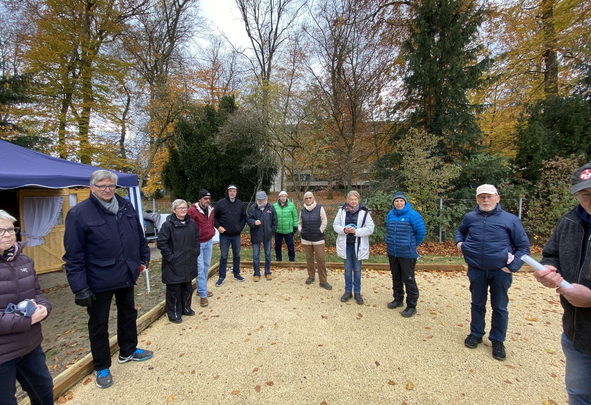 Gruppe von Menschen in warmen Jacken auf Schotterplatz im Herbst