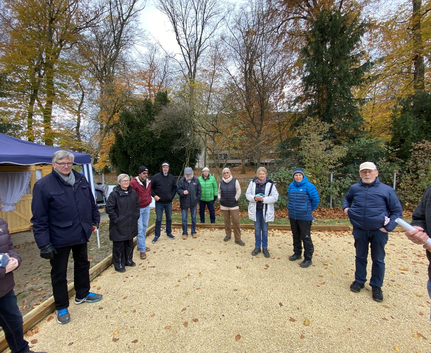 Gruppe von Menschen in warmen Jacken auf Schotterplatz im Herbst