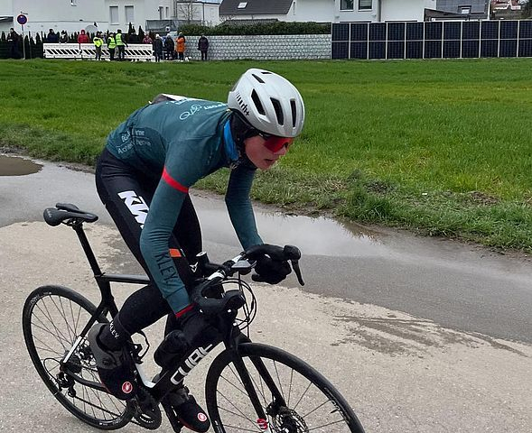 Radsportler in Teamtrikot auf nasser Straße beim Rennen