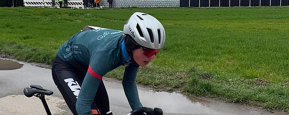 Radsportler in Teamtrikot auf nasser Straße beim Rennen