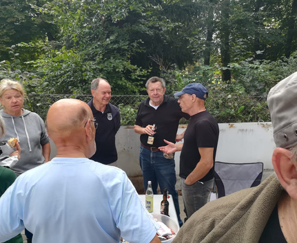 Gruppe älterer Menschen im Gespräch neben Tisch mit Getränken