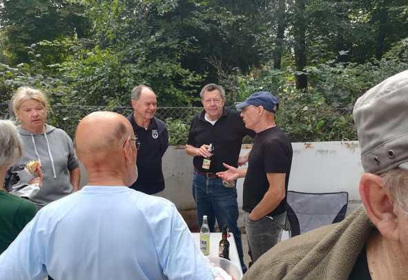 Gruppe älterer Menschen im Gespräch neben Tisch mit Getränken
