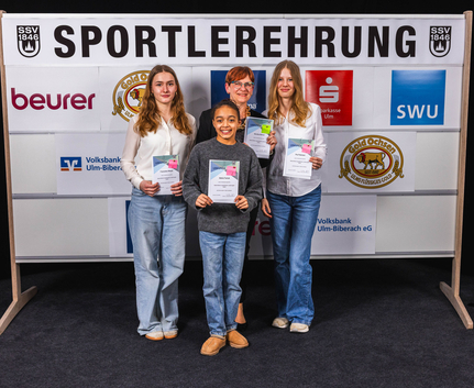 Erfolgreiche Sportlerinnen der Abteilung Turnen Vier Personen mit Urkunden vor Banner SPORTLEREHRUNG