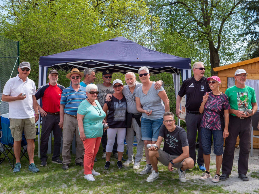 Gruppe älterer Menschen posiert vor Pavillon mit Boulekugeln