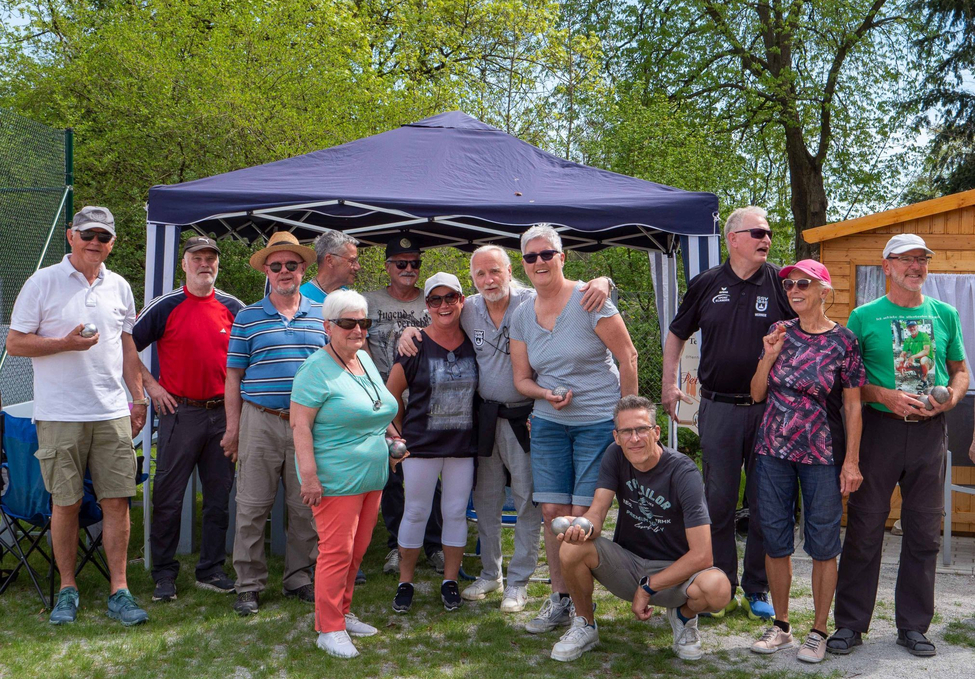 Gruppe älterer Menschen posiert vor Pavillon mit Boulekugeln