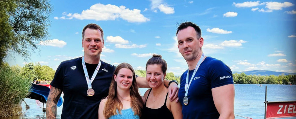 Vier Schwimmer am Seeufer mit Medaillen