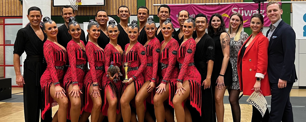 Formationstanzteam in roten Kostümen mit Pokal in Sporthalle
