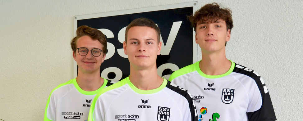 Drei jugendliche Trainer in weißen Ballschul-T-Shirts stehen nebeneinander
