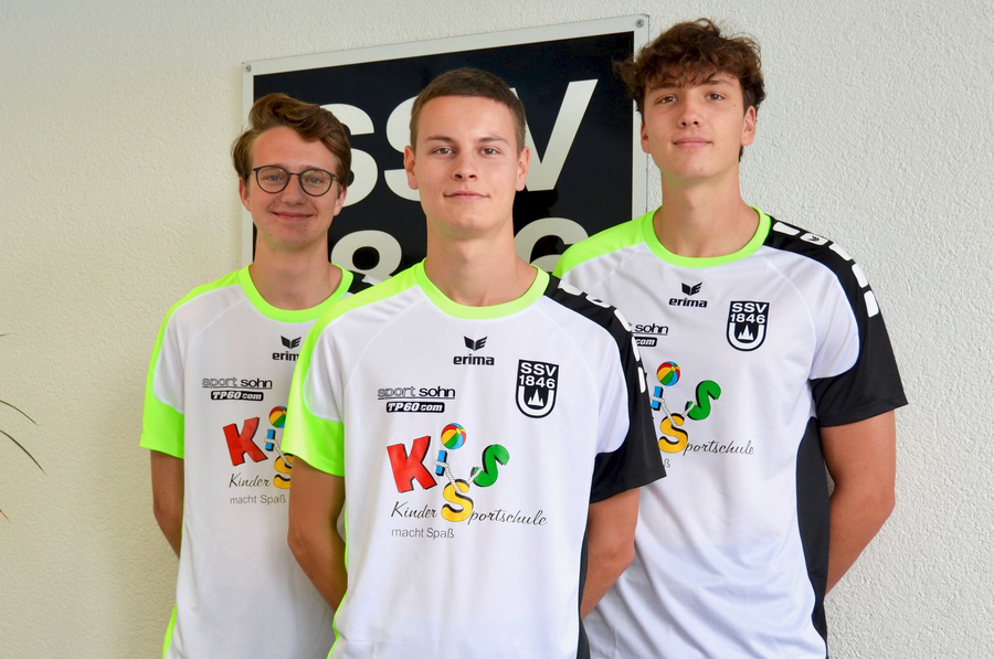 Drei jugendliche Trainer in weißen Ballschul-T-Shirts stehen nebeneinander