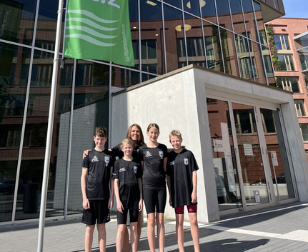 Vier Jugendliche in Schwimmkleidung mit Trainerin vor Sportbad Neckarpark