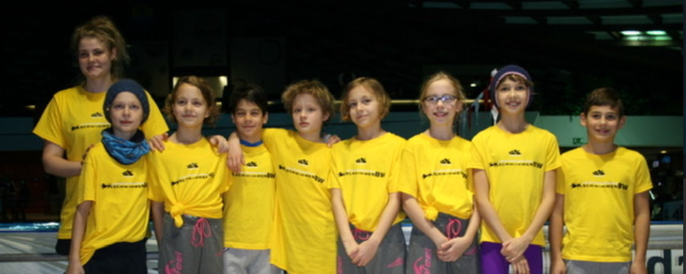 Neun Jugendliche in gelben Teamshirts am Schwimmbeckenrand