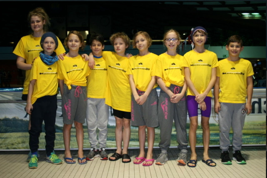 Neun Jugendliche in gelben Teamshirts am Schwimmbeckenrand