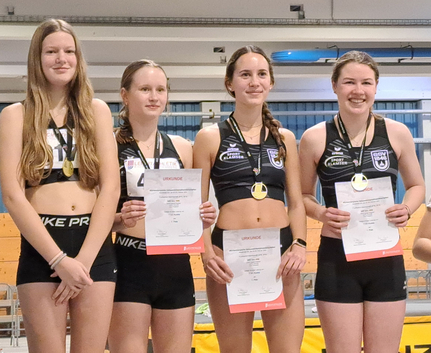vier weibliche Athletinnen in schwarzen Wettkampftrikots mit Medaillen und Urkunden
