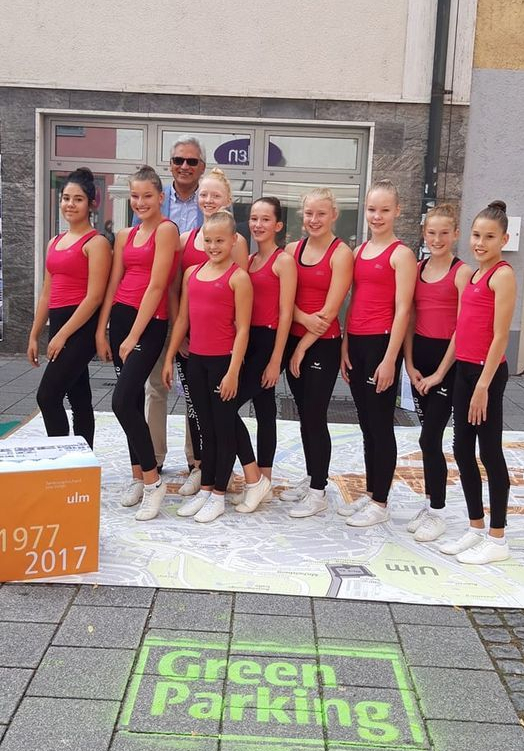 Gruppe junger Sportlerinnen in roten Tops Mann dahinter Green Parking