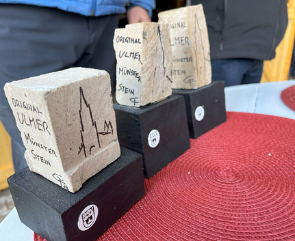 Steinblöcke mit Aufschrift ORIGINAL ULMER MÜNSTER STEIN auf schwarzen Sockeln