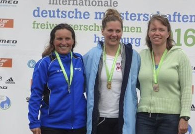 Drei Frauen auf Podium mit Medaillen vor internationale deutsche meisterschaften Banner