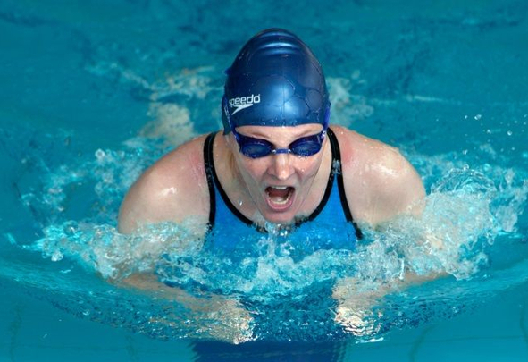 Swimmer in blue Speedo cap swimming breaststroke