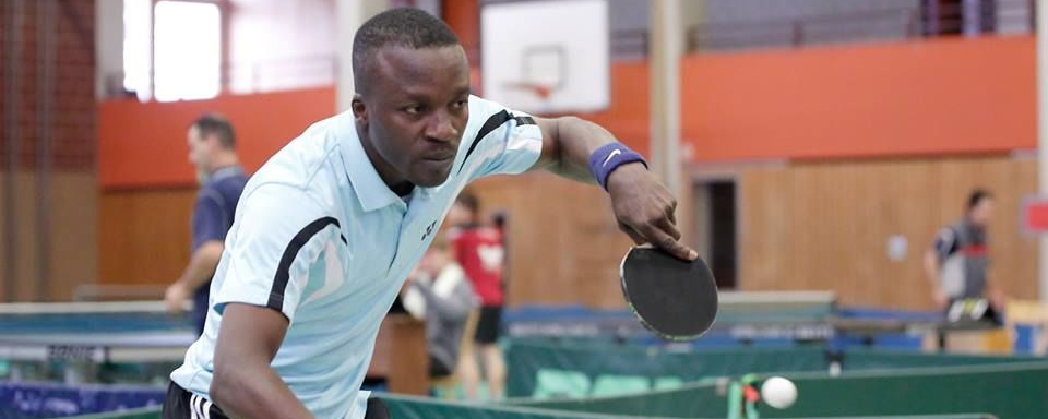 Tischtennisspieler in hellblauem Trikot schlägt Ball über JOOLA Tisch