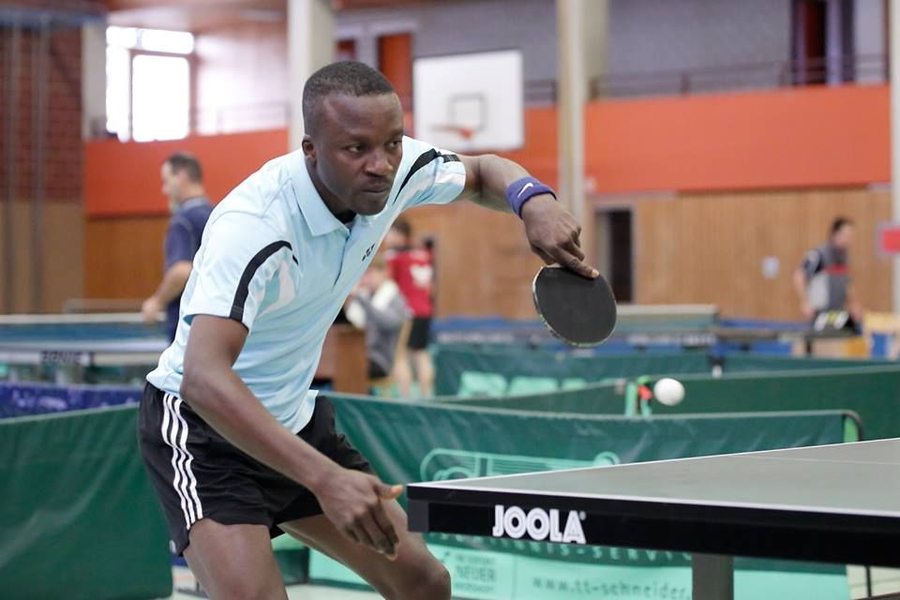 Tischtennisspieler in hellblauem Trikot schlägt Ball über JOOLA Tisch