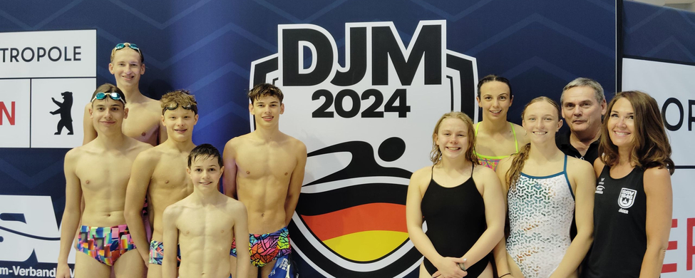 Group of young swimmers and coaches in front of DJM 2024