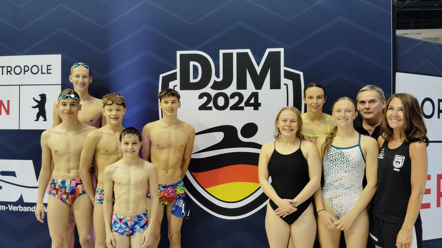 Group of young swimmers and coaches in front of DJM 2024