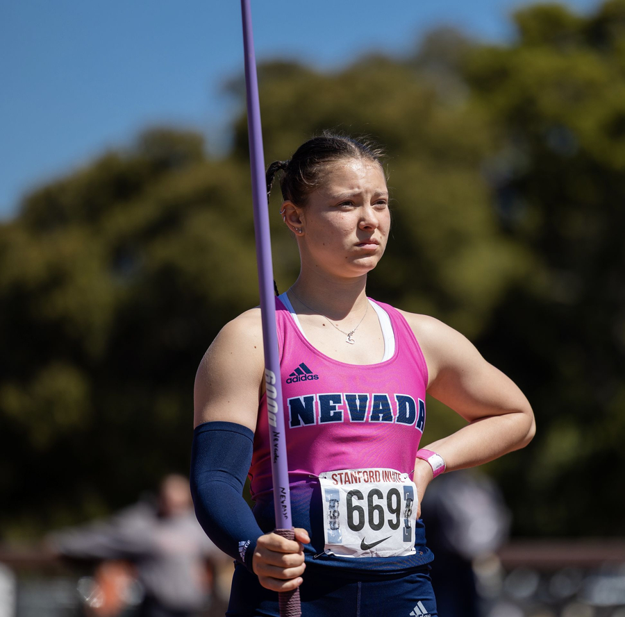 Athlete in pink Nevada singlet holding purple javelin pole