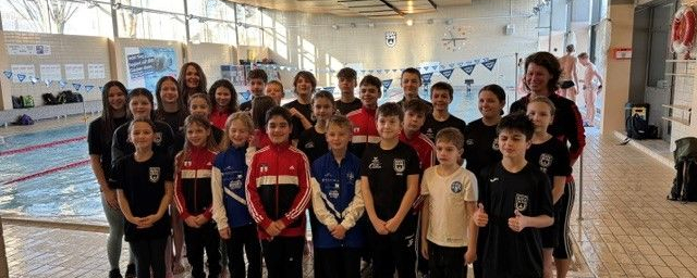 Gruppe jugendlicher Schwimmerinnen und Schwimmer am Hallenbadrand