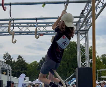Teilnehmer mit Startnummer 60 klettert am Seil im Parcours