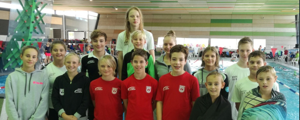 Jugendliche Schwimmerinnen und Schwimmer am Hallenbadbeckenrand