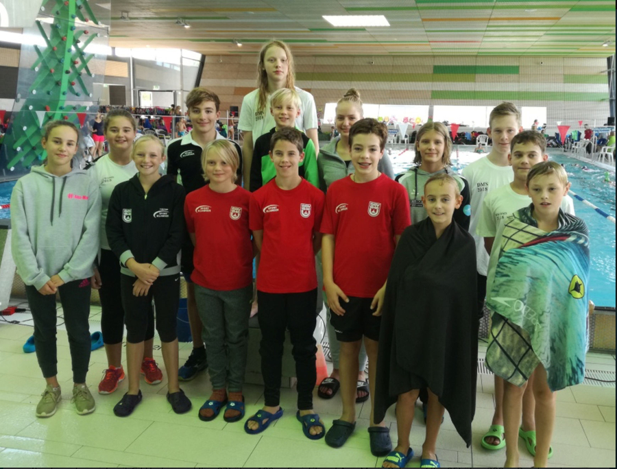 Jugendliche Schwimmerinnen und Schwimmer am Hallenbadbeckenrand