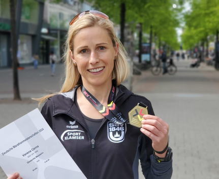 Lächelnde Marathonläuferin mit Medaille und Urkunde Deutsche Marathonmeisterschaften 2024