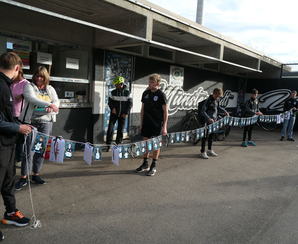 Jugendliche halten lange Geburtstagsgirlande mit Fotos im Stadion