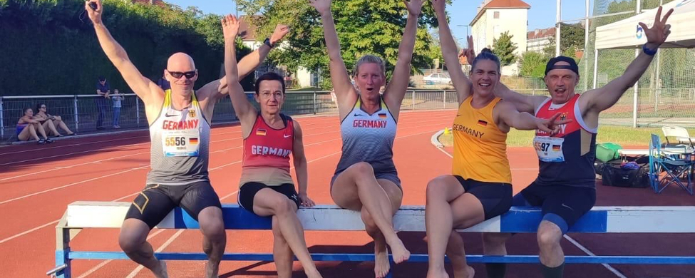 Fünf Athletinnen und Athleten mit Germany-Trikots am Wassergraben