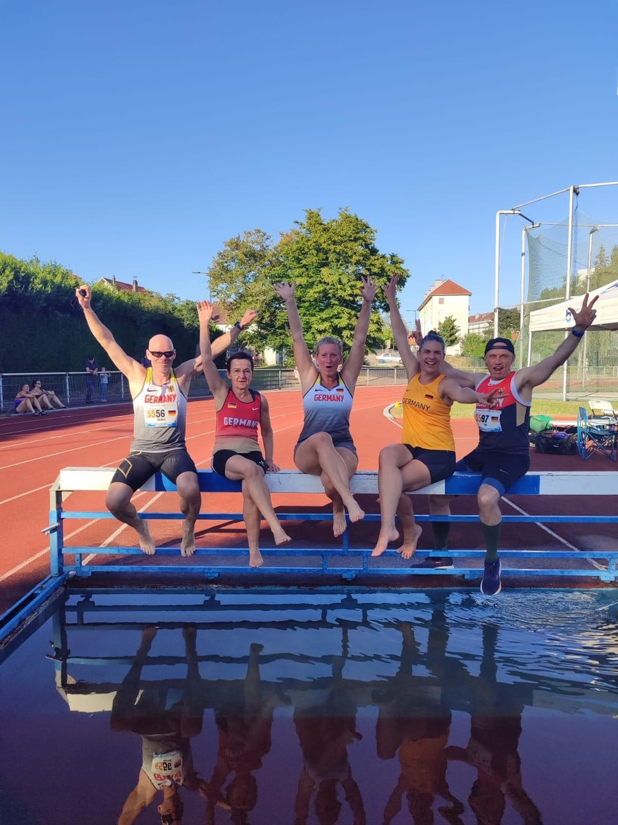Fünf Athletinnen und Athleten mit Germany-Trikots am Wassergraben