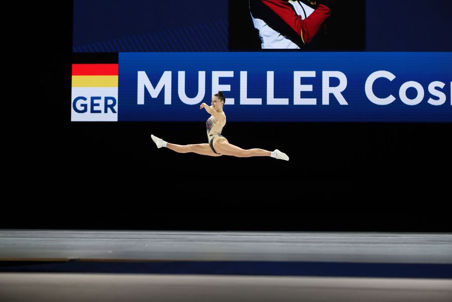 Turnerin im gespreizten Sprung vor Anzeigetafel MUELLER