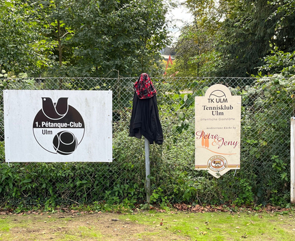 Zaun mit Schild 1. Pétanque-Club Ulm, Schild Tennisklub Ulm und Jacke