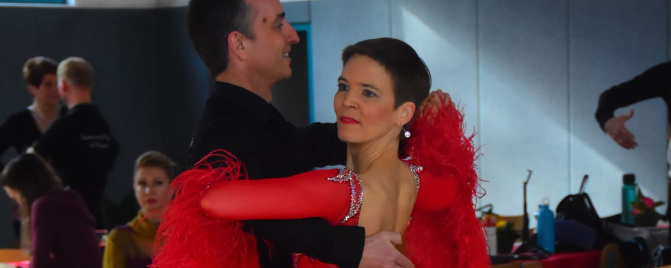 Turnierpaar im Standard Frau in rotem Kleid mit Federn