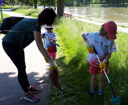 Auch die Kleinsten sind am Start - Ploggin Aktion mit Teilnehmenden in jedem Alter Erwachsene und Kinder sammeln Müll mit Greifzangen am Flussufer