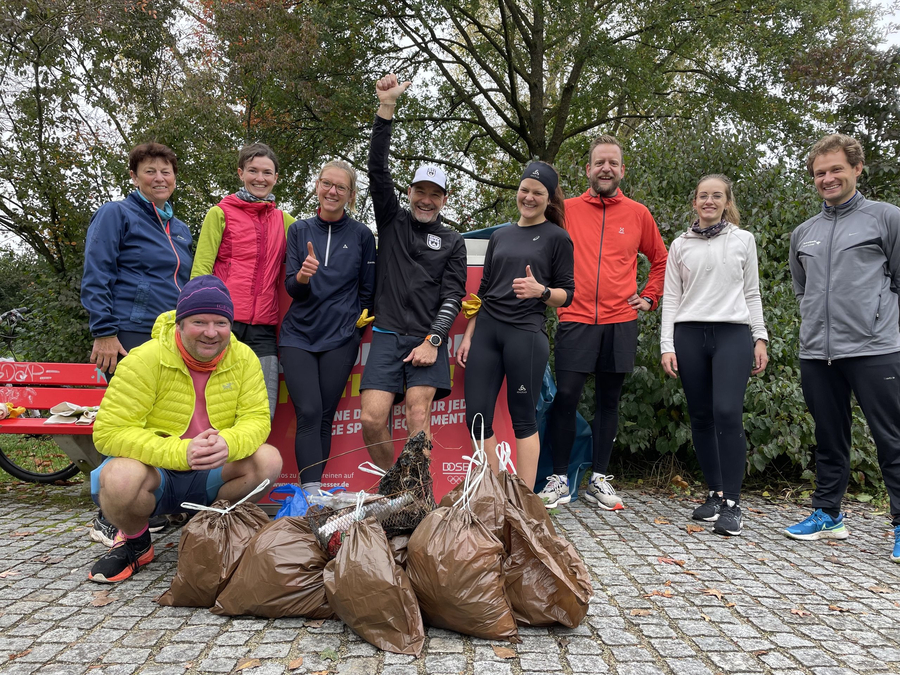 Gruppe von Läuferinnen und Läufern in Sportkleidung mit vollen Müllsäcken