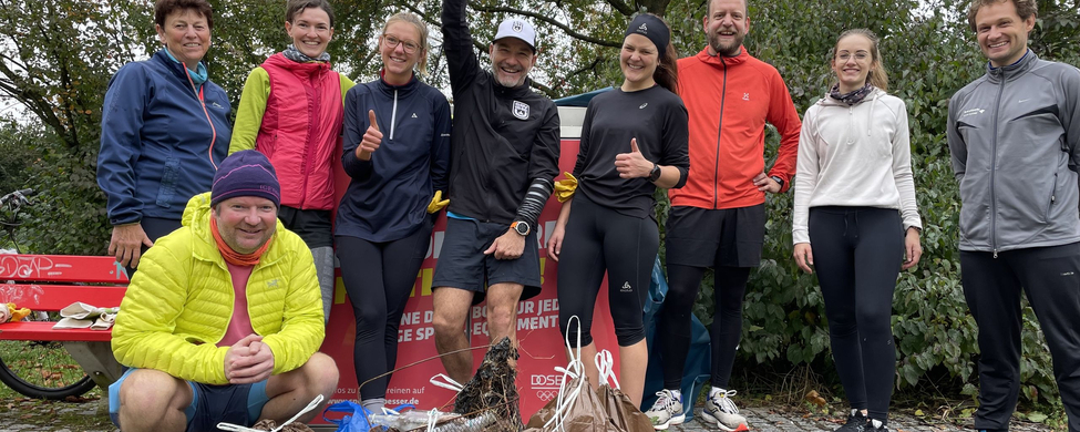 Gruppe von Läuferinnen und Läufern in Sportkleidung mit vollen Müllsäcken