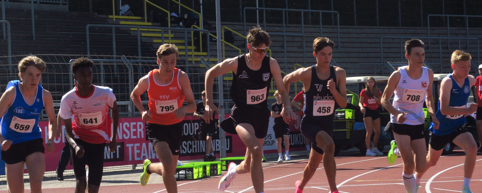 Mehrere junge Läufer starten Sprint auf roter Leichtathletikbahn