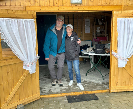 Zwei Personen stehen in geöffneter Holzhütte im Regen