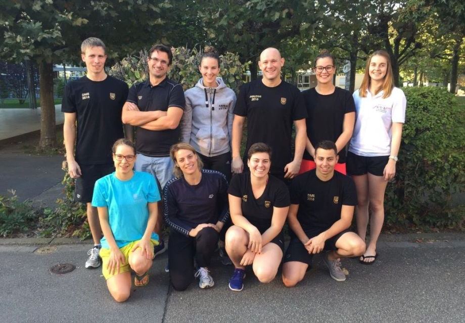 Gruppe von etwa zehn Personen in Sportkleidung im Freien lächelnd