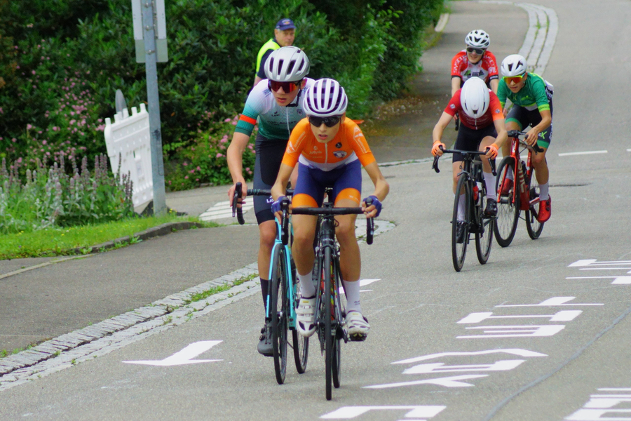 Jugendliche Radfahrer mit orangefarbigem Trikot vorn beim U15-Rennen