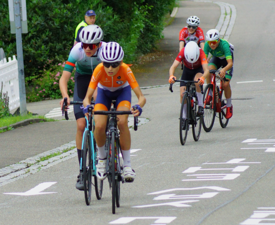 Jugendliche Radfahrer mit orangefarbigem Trikot vorn beim U15-Rennen